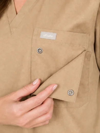 Beige medical scrubs with a chest pocket and a folded flap being held by a hand; small 'efisafe' label on the pocket.