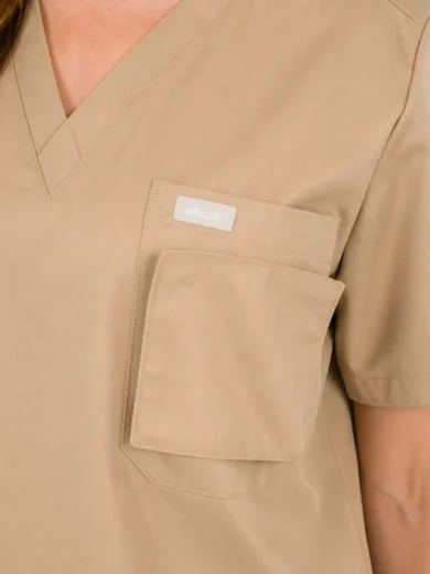 Beige medical scrubs top with a V-neck and a chest pocket featuring an 'efisafe' label and an additional smaller pocket flap nearby.