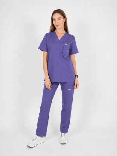 Woman modeling purple medical scrubs (top and pants) with white sneakers against a light background.