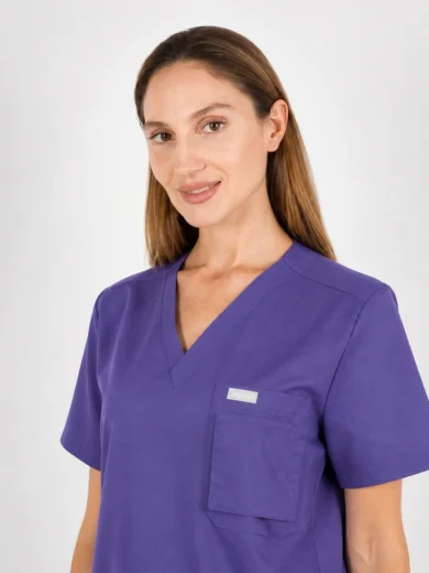 Smiling woman in purple scrubs with a chest pocket facing the camera.