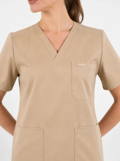 Beige V-neck scrub top with chest pocket and two lower pockets on a person.