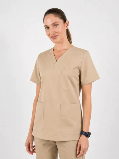 Woman wearing beige medical scrubs with a V-neck top and multiple pockets, standing against a light background.