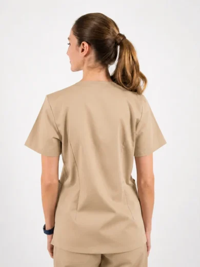 Back view of a person wearing tan scrubs with a ponytail, standing against a light background, showing the short-sleeve top and matching pants.