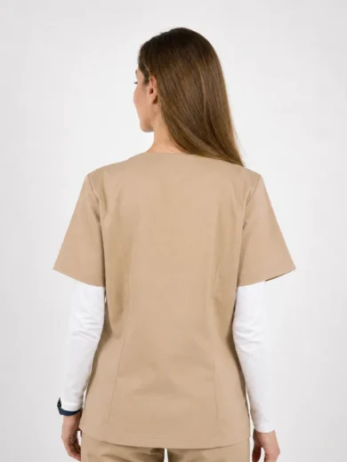 Back view of a person wearing a beige scrub top over a white long-sleeve shirt, standing against a light background.