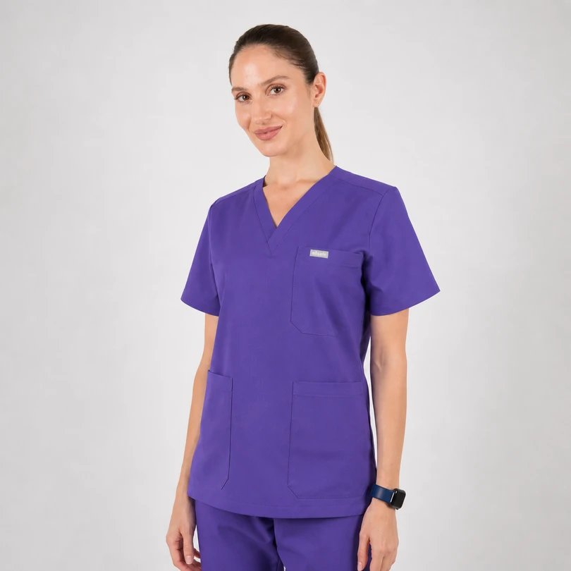 Woman in purple medical scrubs with V-neck and short sleeves, standing against a neutral backdrop.