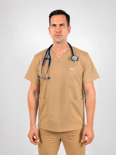 Male healthcare professional in tan scrubs with a stethoscope around his neck, standing against a neutral backdrop.