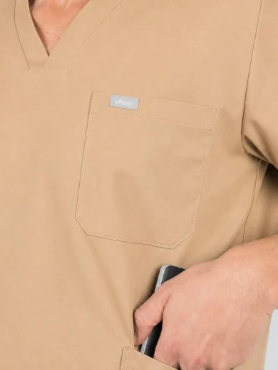Close-up of tan scrubs with a chest pocket and a hand slipping a smartphone into the pocket.