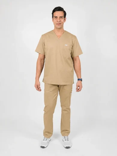 Man wearing tan medical scrubs (top and pants) standing and facing the camera in a neutral studio.