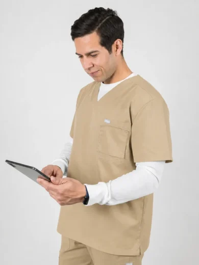 Male healthcare worker in beige scrubs using a tablet