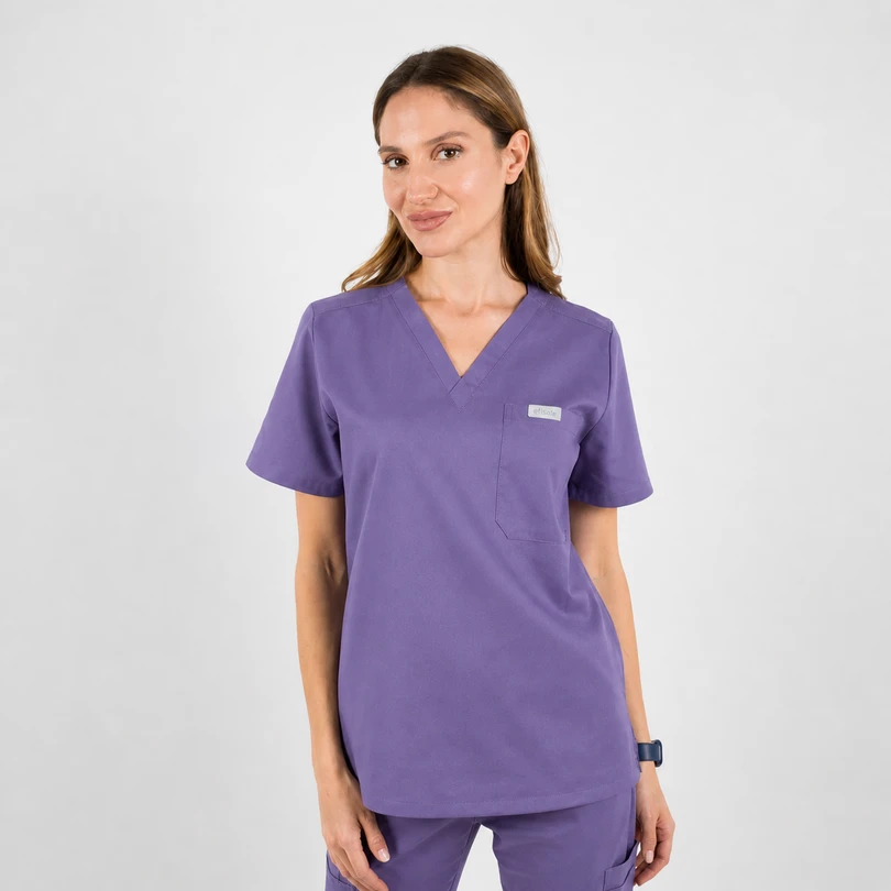 Woman in purple medical scrubs with a V-neck top and chest pocket, standing against a light background.