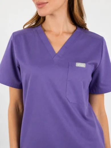 Purple V-neck scrub top with short sleeves and a chest pocket with a small brand tag on the pocket edge.
