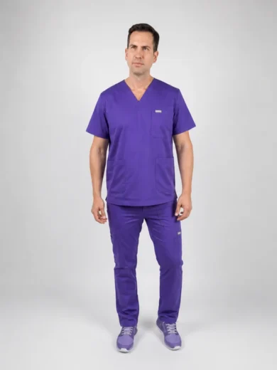 Male medical professional in purple scrubs standing against a light gray backdrop.
