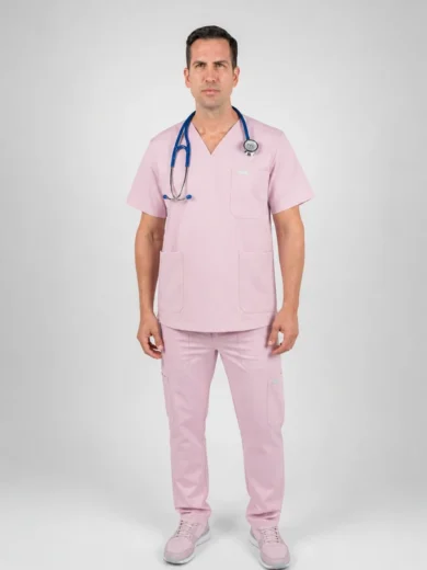 Male healthcare professional standing in pink scrubs with a stethoscope around his neck against a light gray backdrop, facing the camera.