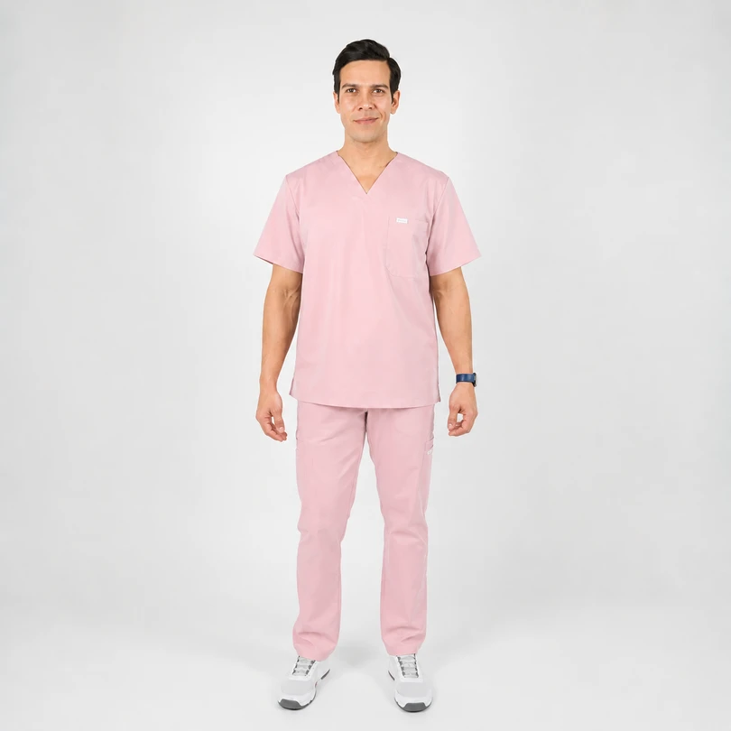 Adult male model in light pink medical scrubs standing against a white backdrop, hands at sides.