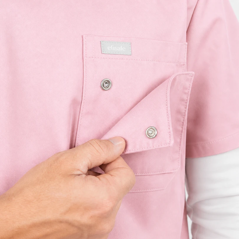 Close-up of a pink shirt pocket with a hand fastening a metal snap button that secures the flap.