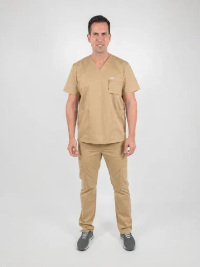 Man in beige medical scrubs standing facing camera in a studio, with V-neck top and cargo pants.