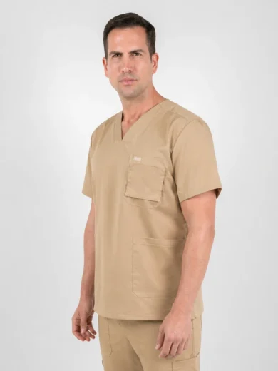 Adult man in tan medical scrubs stands against a light gray background, facing slightly to the right with a neutral expression.