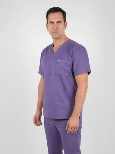 Man modeling purple medical scrubs with V-neck top and multiple pockets, standing against a light gray background, facing slightly to the left.