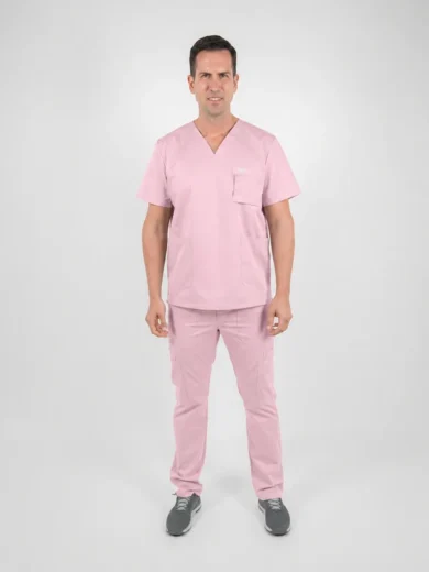 Man wearing pink medical scrubs, a V-neck top with chest pocket and cargo-style pants, standing against a light gray studio background.