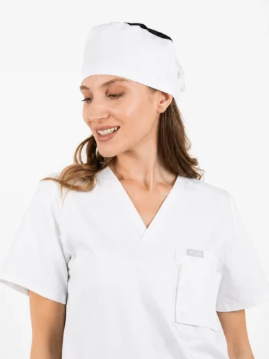 Woman in white medical scrubs and cap, smiling and looking to the side.