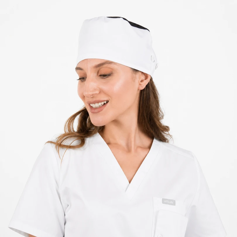 Smiling woman in white medical scrubs and cap, looking to her left against a clean white background.