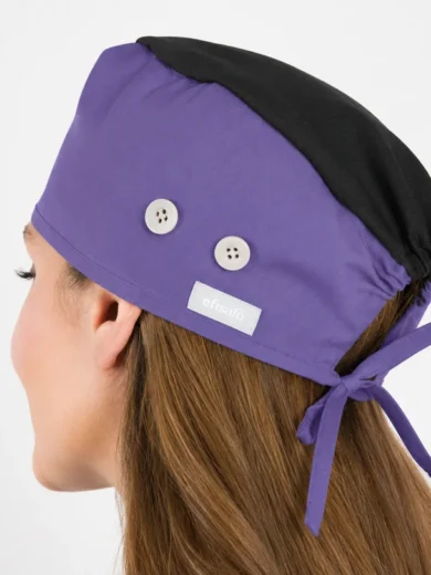 Side view of a purple medical scrub cap with two white buttons and a back tie on a person’s head.