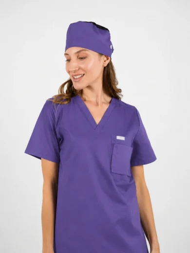Woman in purple medical scrubs with V-neck top and matching cap, smiling slightly to the side.