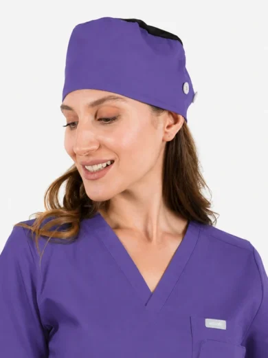 Woman in matching purple scrubs and surgical cap, smiling softly to the side.