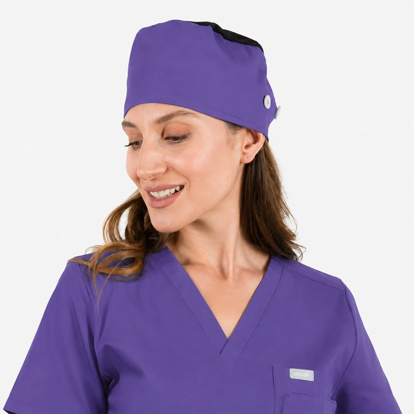 Woman in matching purple scrubs and surgical cap, smiling softly to the side.