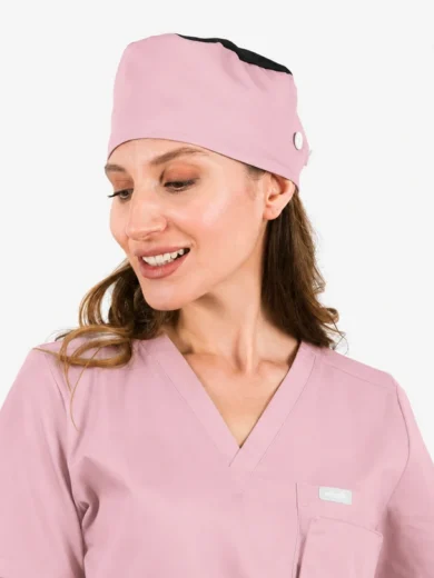 Woman in pastel pink scrubs and matching scrub cap, smiling and looking to her left.