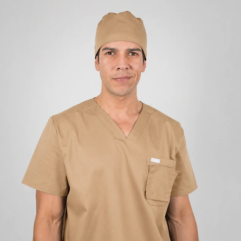 Front-facing man in tan medical scrubs and cap, against a light gray background.
