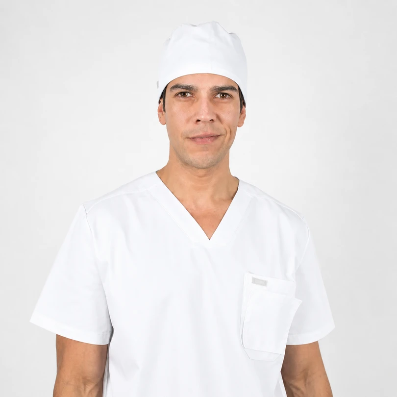 Male healthcare professional wearing white scrubs and a surgical cap, facing the camera with a neutral expression.
