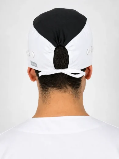 Back view of a person wearing a white surgical cap with a black top, tied at the back at the nape of the neck
