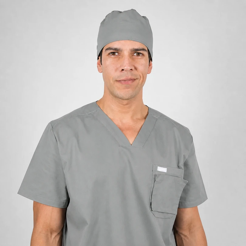 Male surgeon in gray scrubs and cap, looking at the camera with a neutral expression.