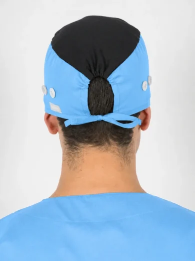 Back view of a healthcare professional wearing a blue surgical cap with a black top panel, tied at the back, and blue scrubs.