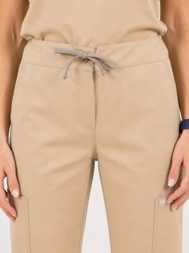 Beige drawstring-waist pants with front fly, side pockets, and thigh cargo pocket (close-up view).