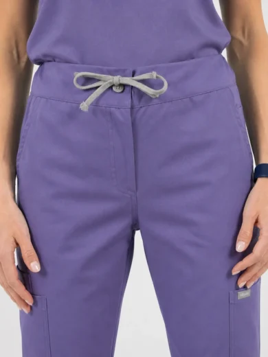 Person wearing purple scrub pants with a gray drawstring tied at the waist and front pockets visible, a smartwatch on the left wrist behind the hand.