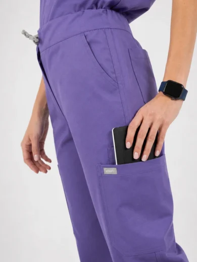 Purple scrubs with a phone tucked into the side pocket and a smartwatch on the wrist.
