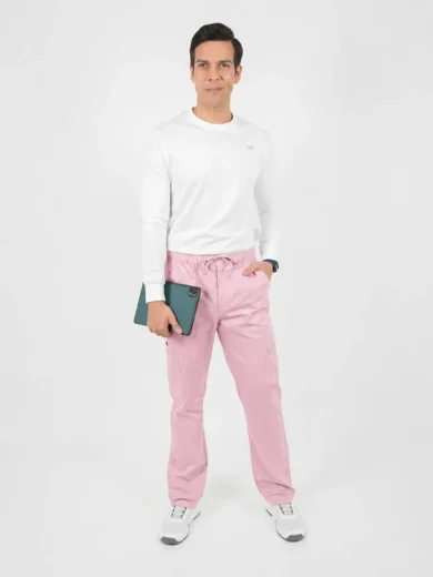 Man in a white long-sleeve shirt and pink jogger-style pants holds a tablet while standing against a white backdrop.