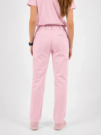 Back view of a person in pastel pink scrubs pants with an elastic waistband and cargo pockets, wearing a matching pink top and pink sneakers.