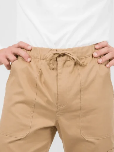Close-up of a person wearing beige drawstring cargo pants with hands on hips and a white shirt.