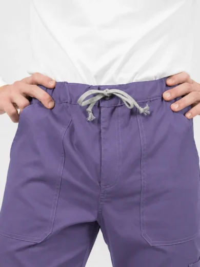 Adult wearing purple drawstring pants with front pockets, hands on hips in a white shirt.