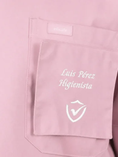 Pink medical scrubs pocket with embroidered name 'Luis Perez Higienista' and white emblem